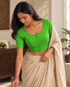 Meadow green front-hook saree blouse worn with a beige linen saree, adjusting the pallu indoors